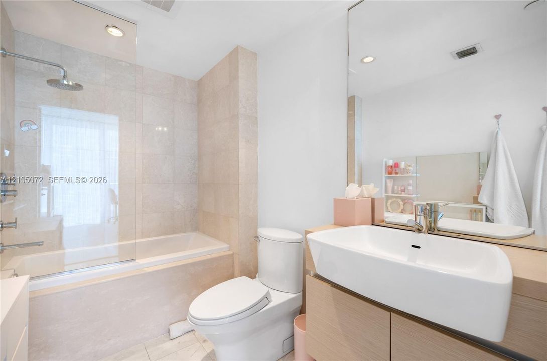 Secondary bathroom with bathtub, glass shower screen, and single-sink vanity.