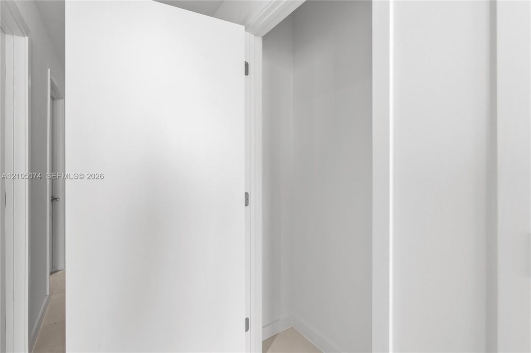 Interior closet featuring a clean, white-painted finish, smooth door paneling, and brushed nickel hardware