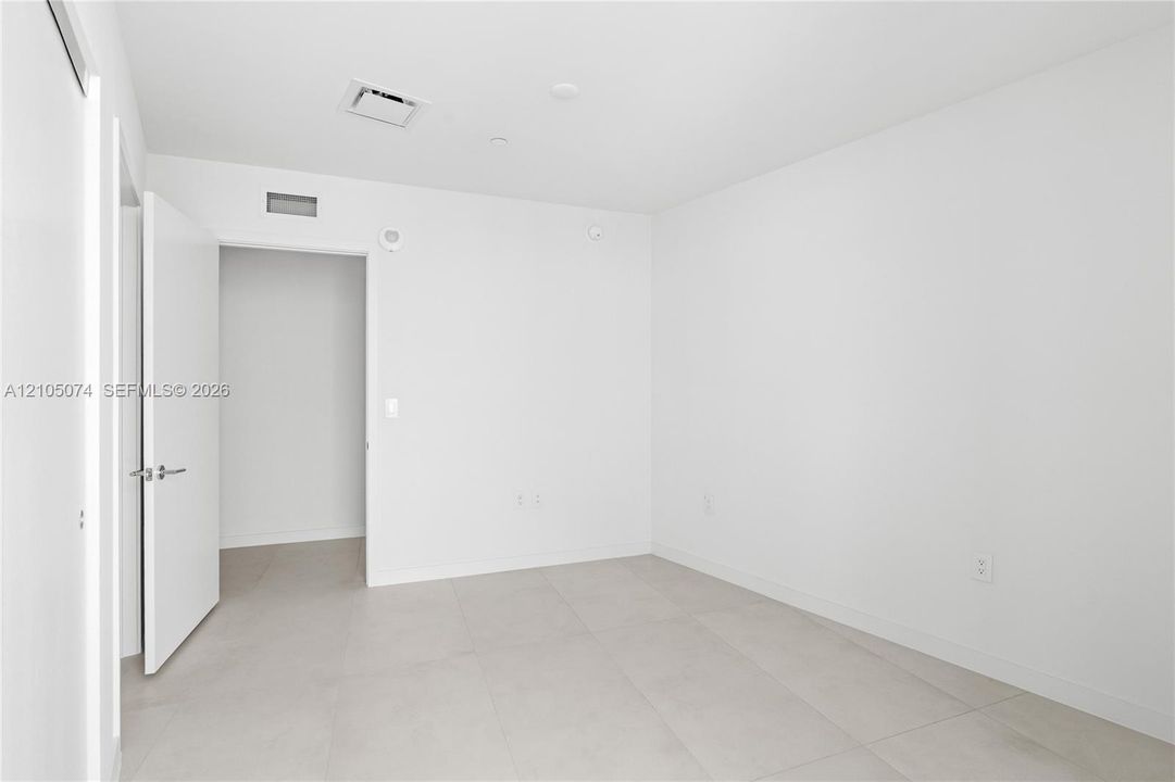 Neutral-toned interior space featuring light-colored tile flooring and minimalist, crisp white walls