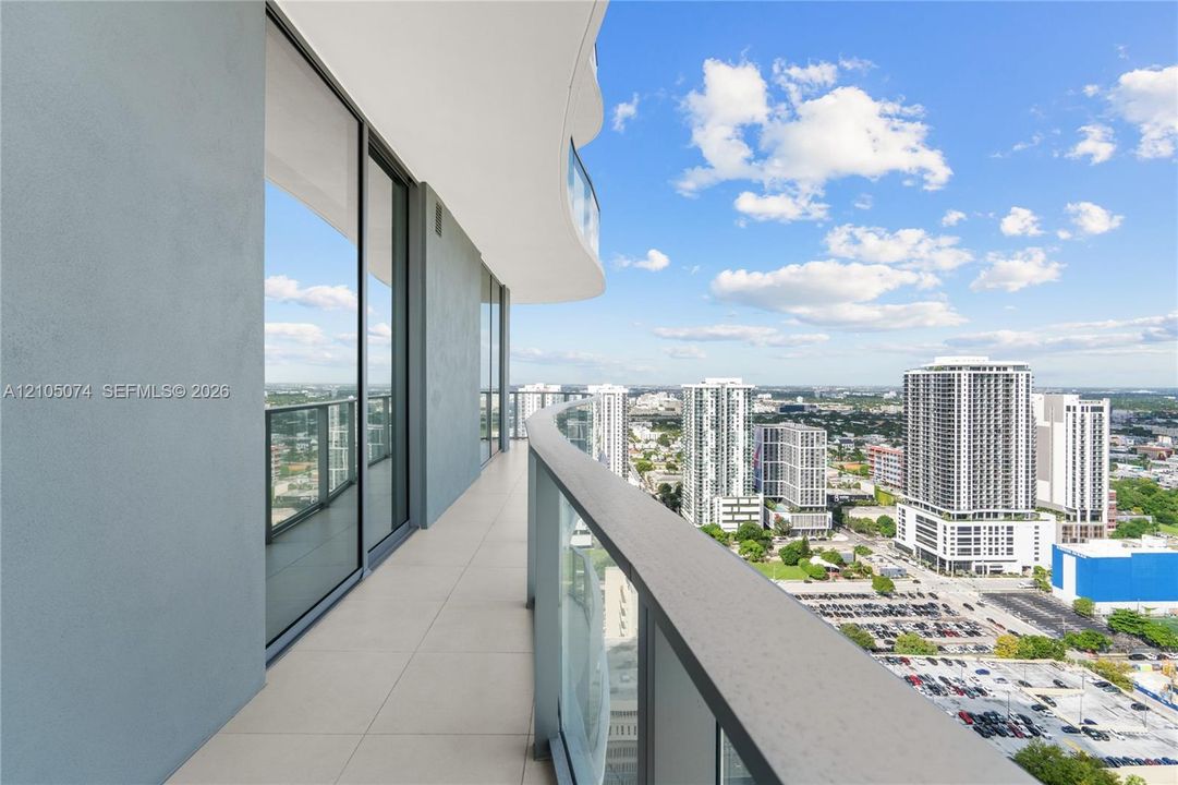 Curved exterior balcony featuring tile flooring, floor-to-ceiling glass paneling, and a structural railing