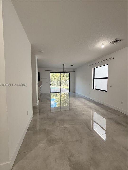 Open-concept interior featuring large-format tile flooring, recessed lighting, and sliding glass doors leading to the exterior