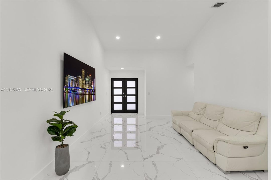 High-ceilinged entry featuring stone-finish flooring with veining, recessed lighting, and black-framed double doors with inset glass panels