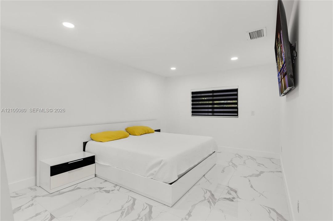 Room featuring polished stone-look flooring, recessed ceiling lighting, and a window with dual-layer zebra roller shades