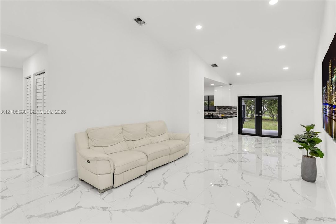 Large-format polished tile flooring, recessed ceiling lighting, and black-framed double glass doors