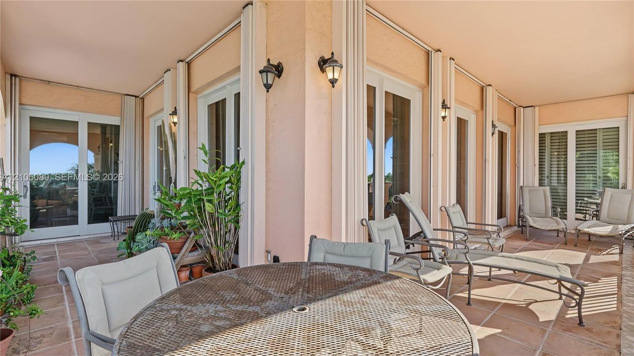 Covered terrace featuring tile flooring, multi-pane glass doors, and wall-mounted exterior lighting