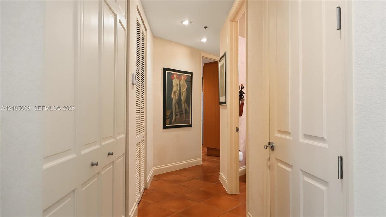 Hallway featuring terracotta tile flooring, recessed ceiling lighting, and multiple interior paneled doors with satin nickel hardware