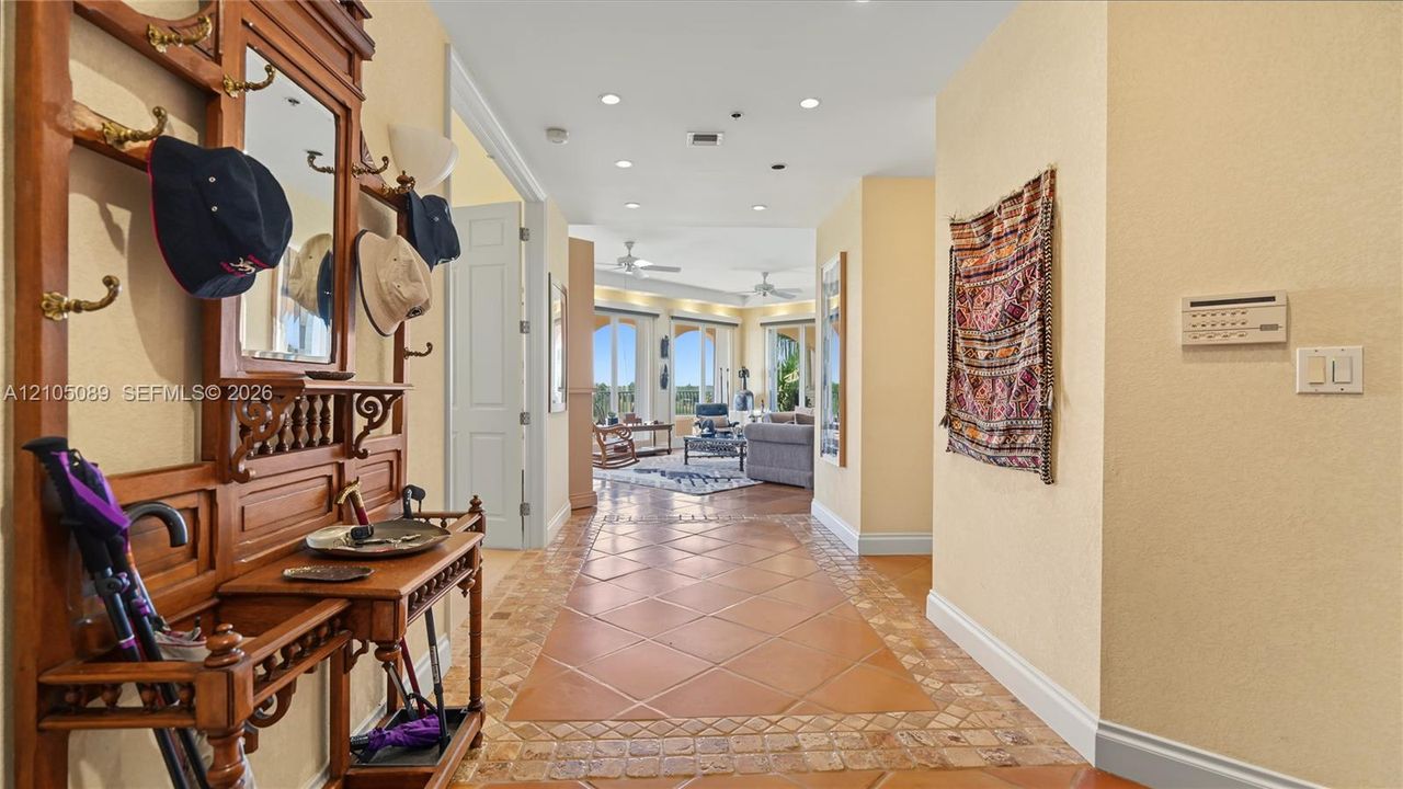 Entryway featuring terracotta-toned tile flooring with decorative mosaic border, recessed lighting, and wall-mounted security panel
