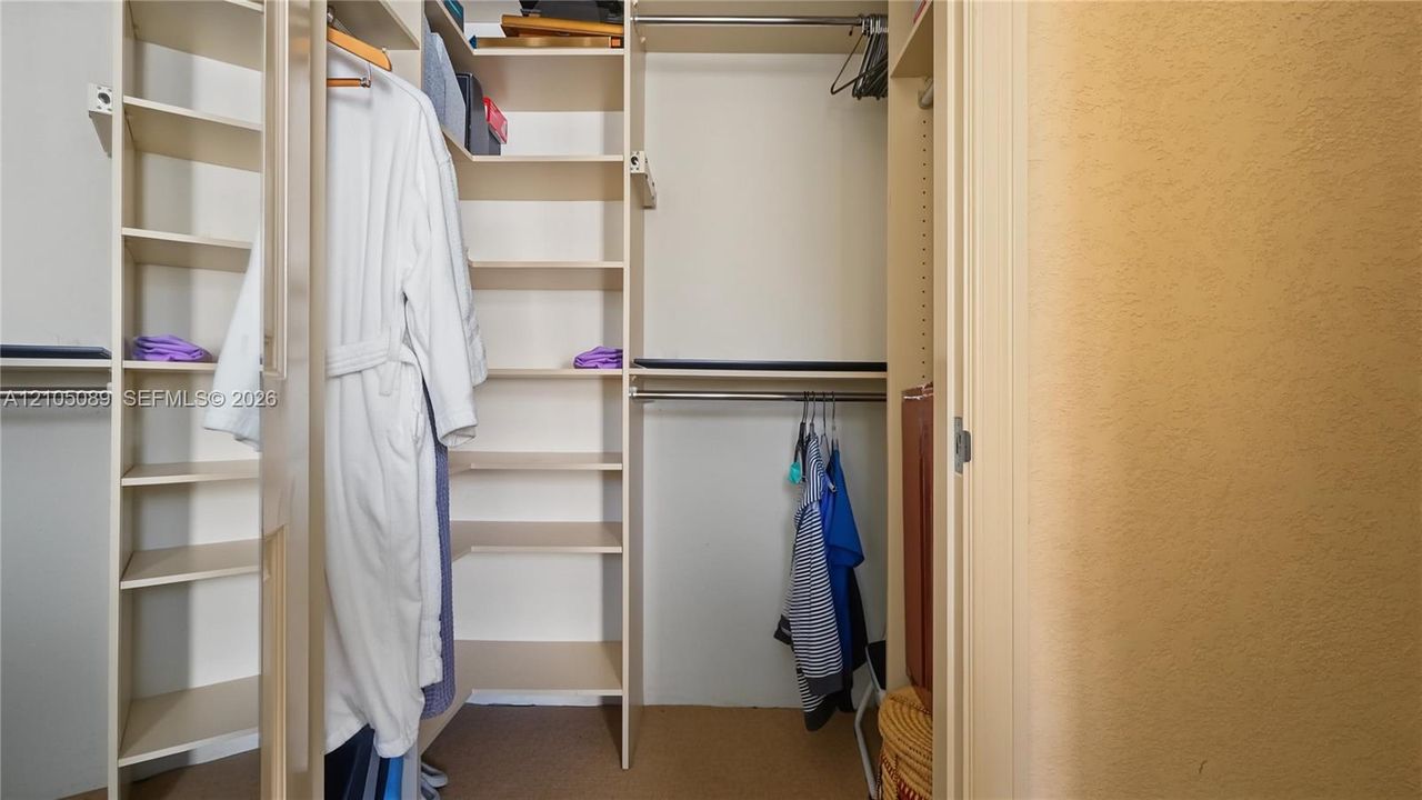 Walk-in closet featuring extensive built-in shelving and dual metal garment rods