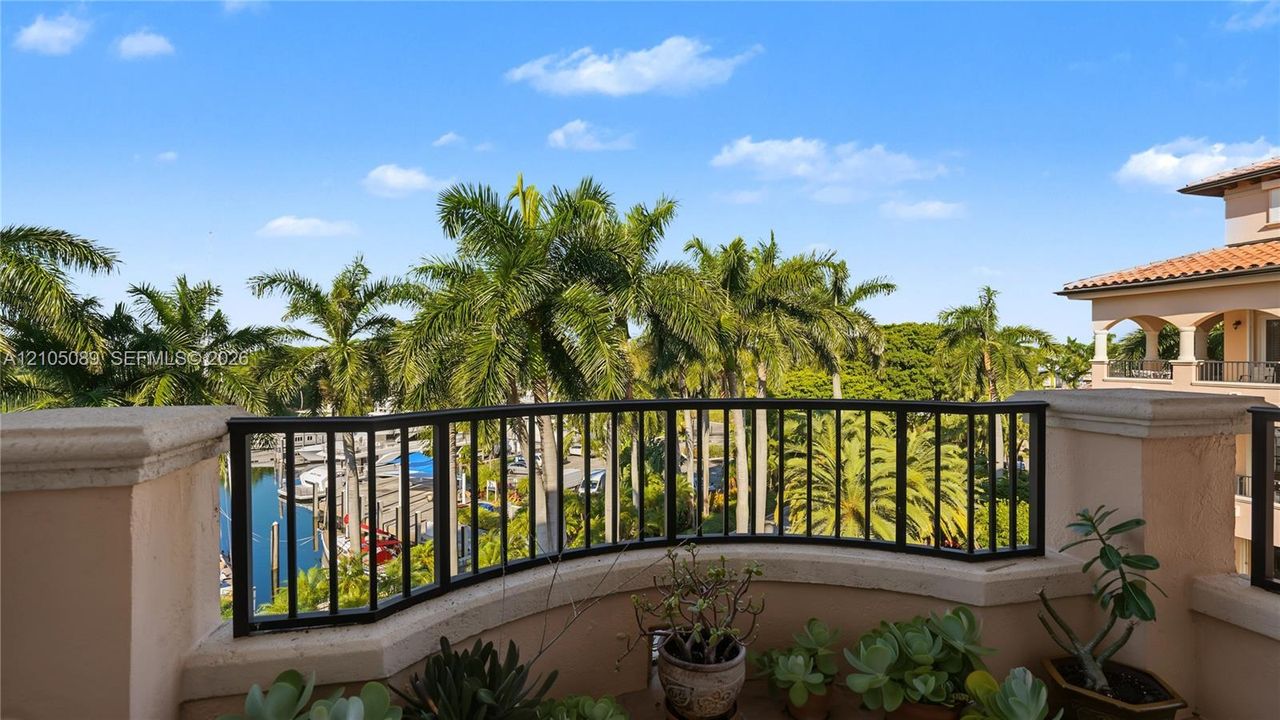 Covered balcony featuring a curved stucco wall, black metal railing, and terra cotta roof tiles
