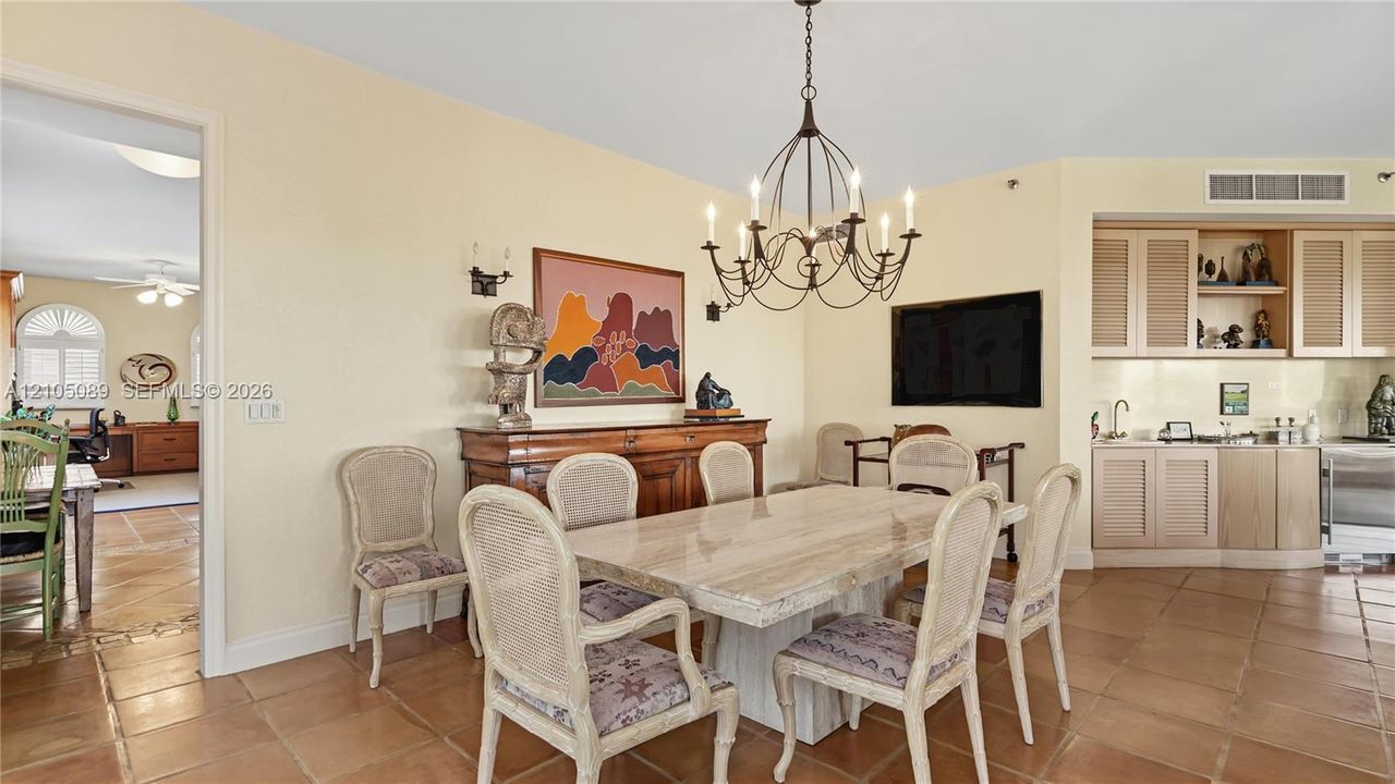 Dining area featuring tile flooring, a multi-arm metal chandelier, and a built-in cabinetry unit with an integrated sink and countertop
