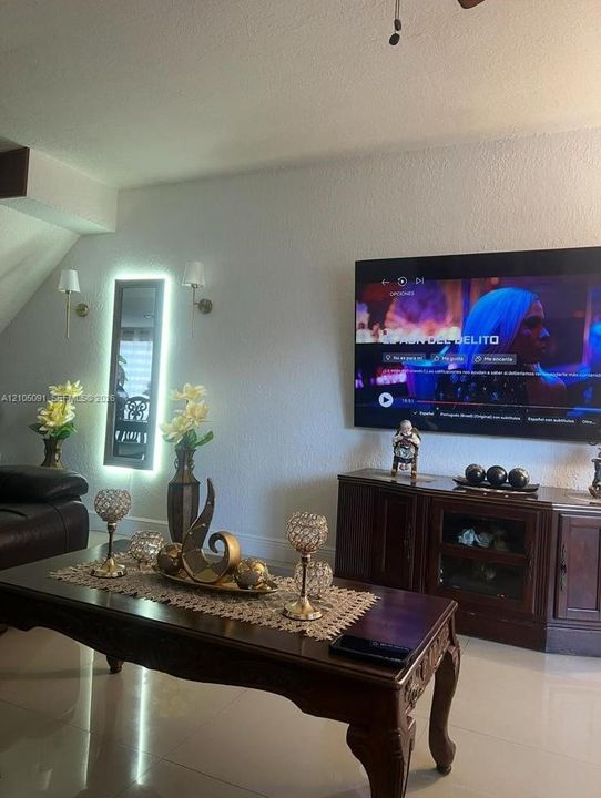 Wall-mounted LED backlit mirror, two brass-toned wall sconces with drum shades, and polished tile flooring