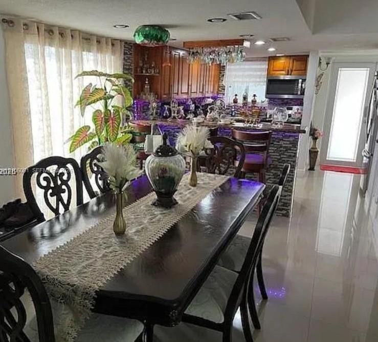 Kitchen featuring wood cabinetry, stone-tiled breakfast bar, recessed ceiling lighting, and large-format tile flooring