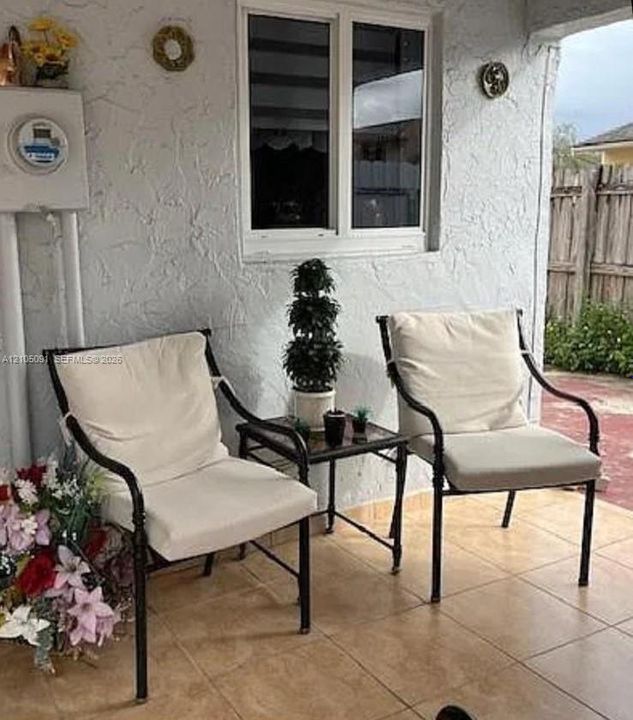 Covered patio featuring ceramic tile flooring, textured wall finish, and a double-pane horizontal sliding window
