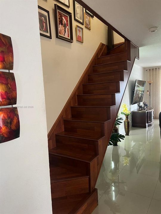 Staircase featuring dark wood-finish treads and risers complemented by polished light-toned floor tiling