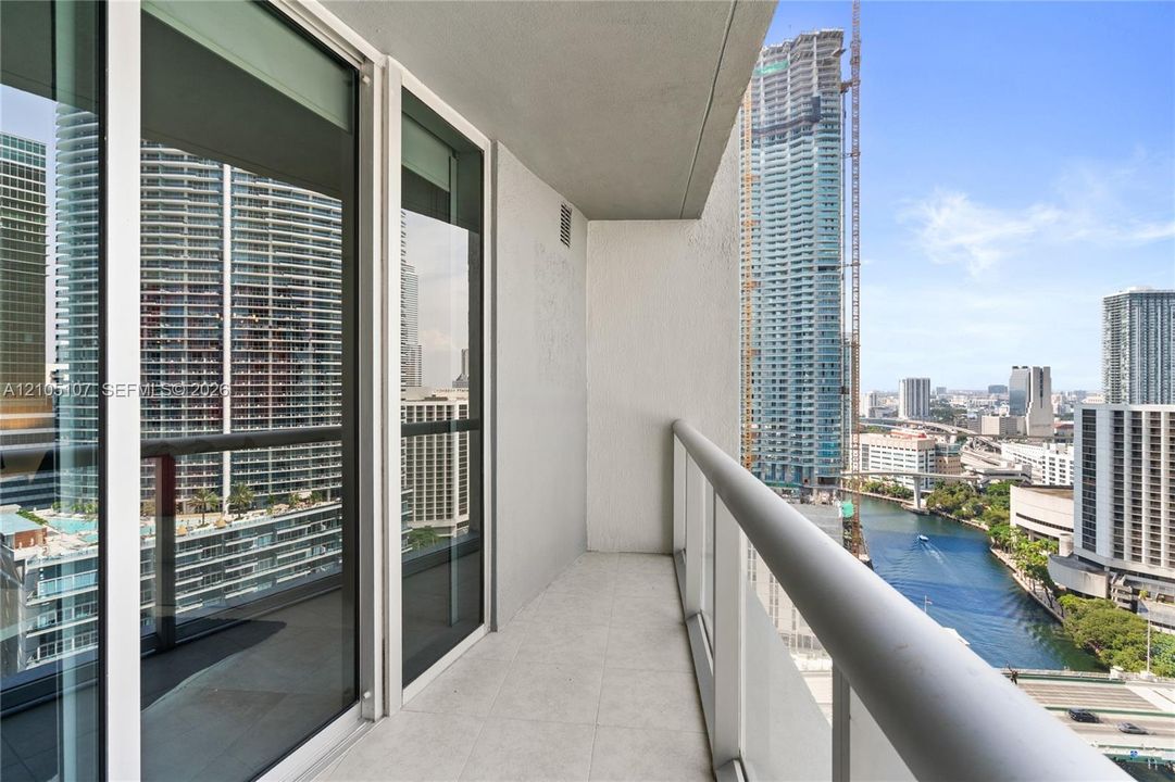 Balcony with tiled flooring, clear glass railing, and sliding glass doors