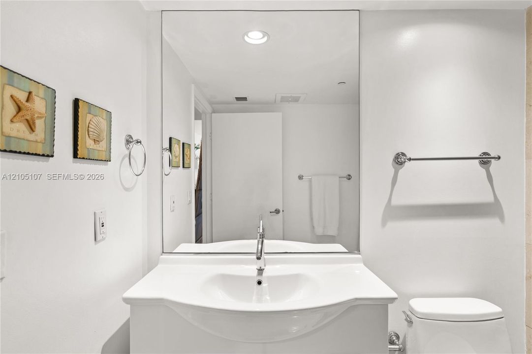 Recessed ceiling lighting illuminates a vanity with an integrated sink and chrome faucet