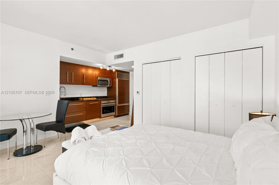 Integrated kitchen with wood-finish cabinetry, stainless steel appliances, and dark countertops