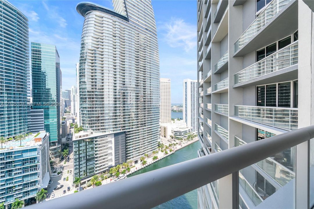 Balcony with glass railings overlooking a cityscape and a waterway