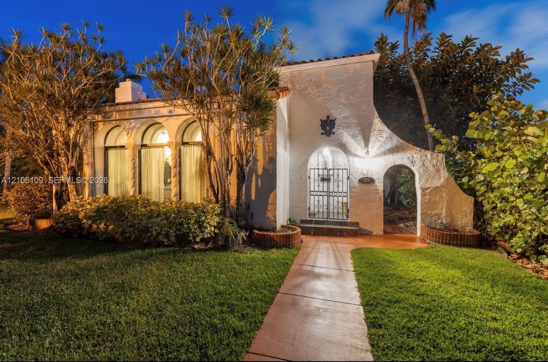 Stucco exterior with an arched entry, prominent arched windows, and an ornamental gate