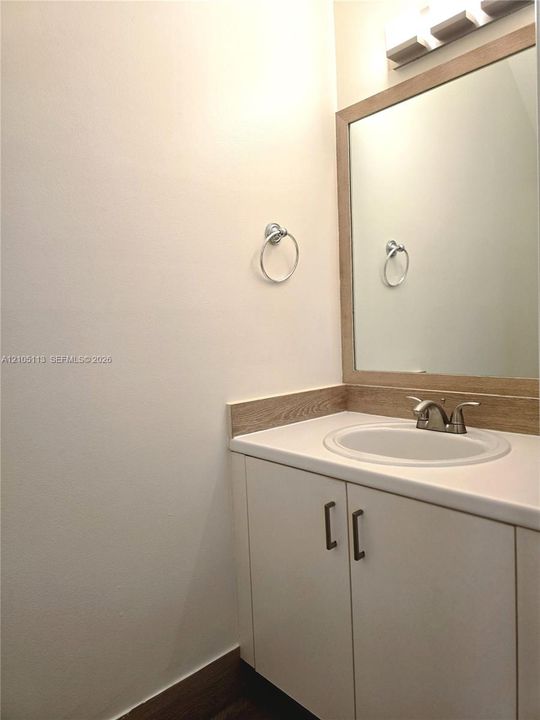 Vanity with wood-finish countertop, integrated sink, and white cabinetry
