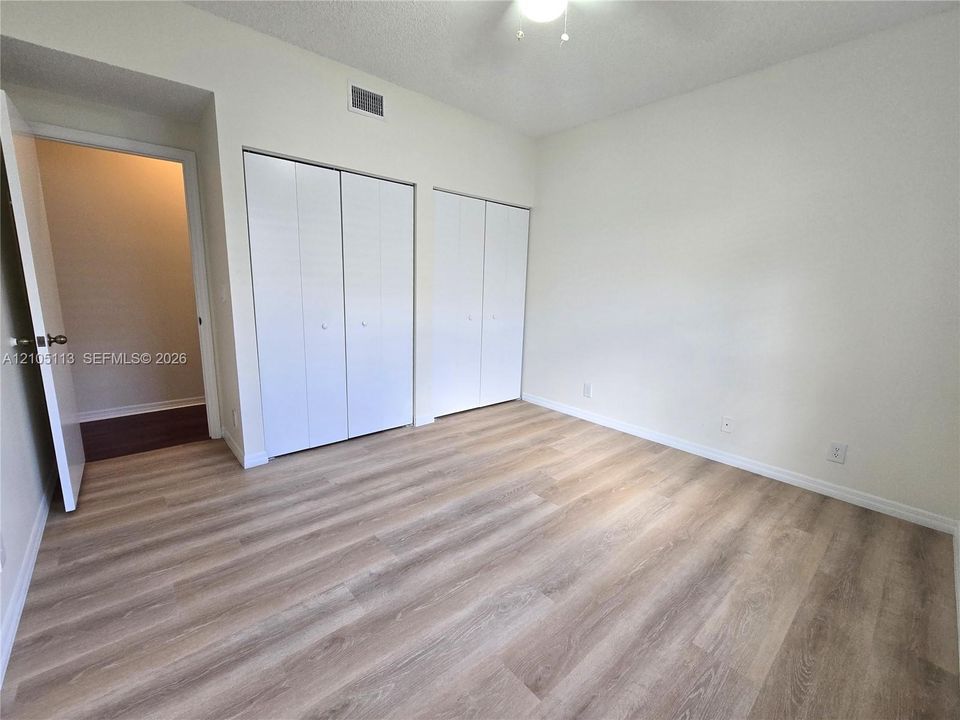 Light wood-finish flooring throughout, two bi-fold door closets, and a ceiling fan