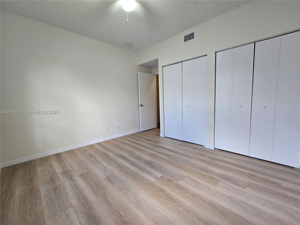 Light wood-finish flooring, neutral wall tones, and dual closet installations