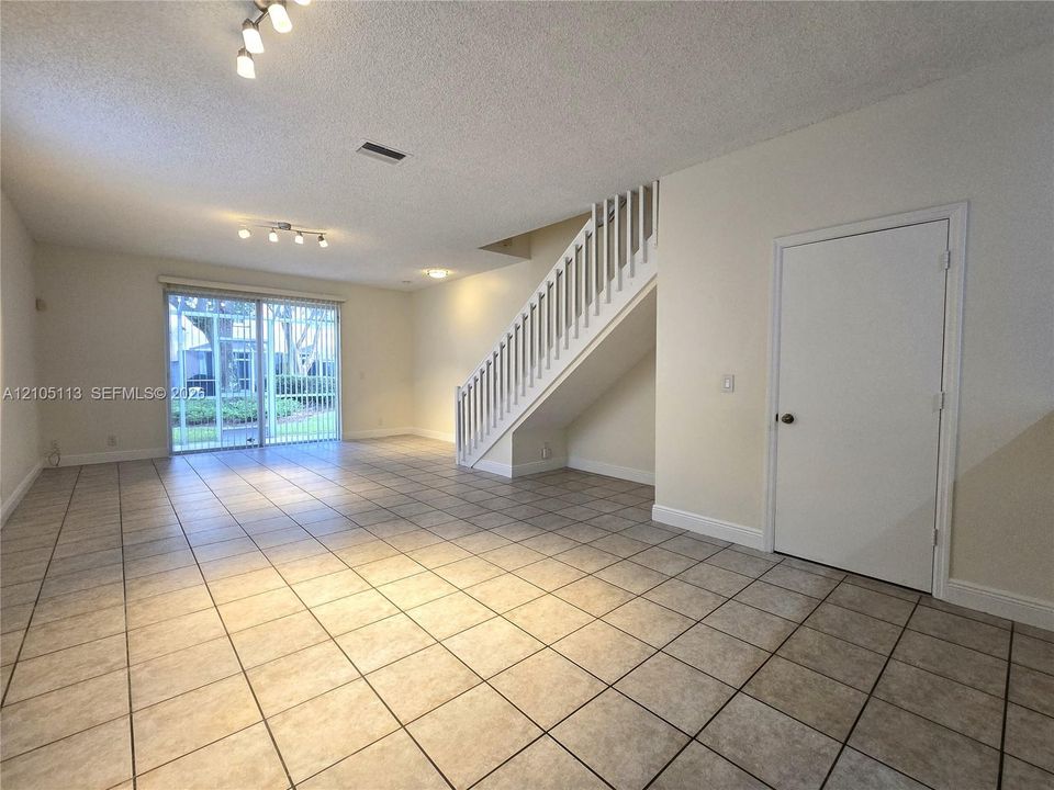 Expansive tile flooring, sliding glass doors to exterior, white painted staircase, and recessed lighting
