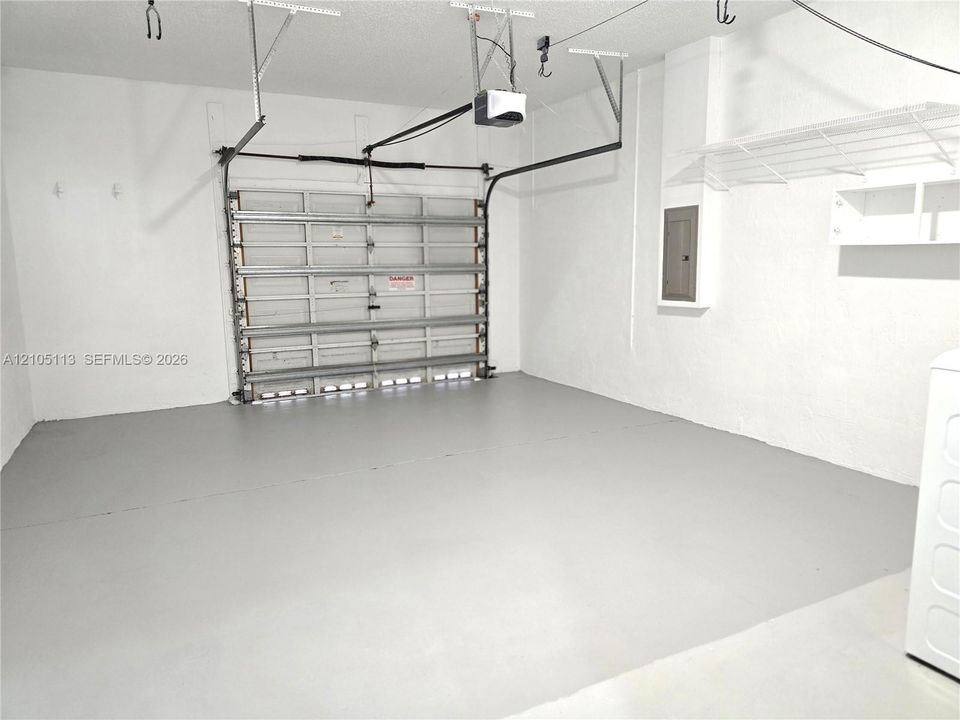 Garage with a finished floor, automatic garage door, and built-in overhead shelving