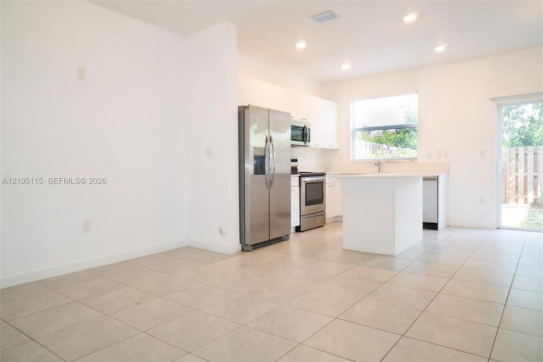 Kitchen featuring white cabinetry, an island, stainless steel appliances, and tile flooring