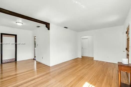 Wood-finish flooring, decorative corbel beam detailing, and a solid wood entry door with stained glass inlay
