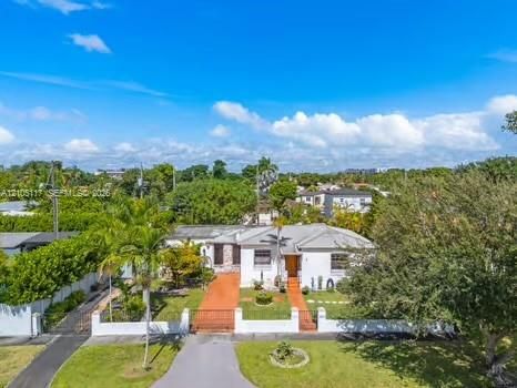 Single-story residence featuring a light-toned exterior, concrete tile roof, gated masonry wall, and paved driveway
