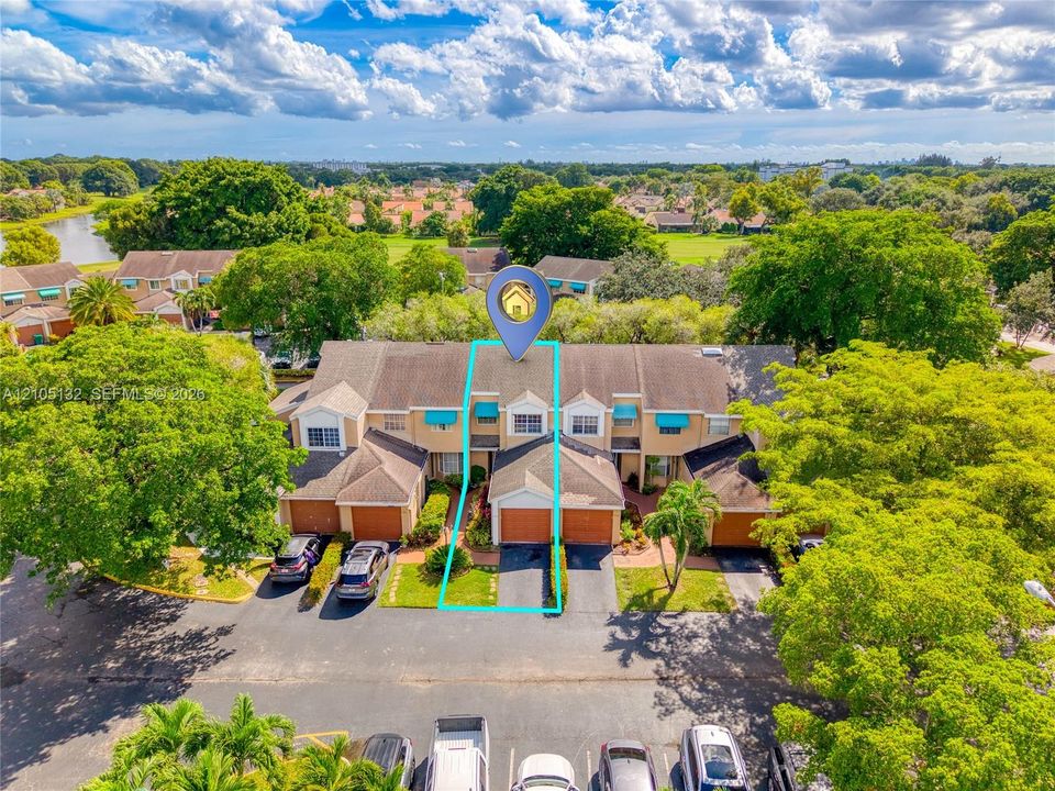 Townhome with a single-car garage, established landscaping, and awnings