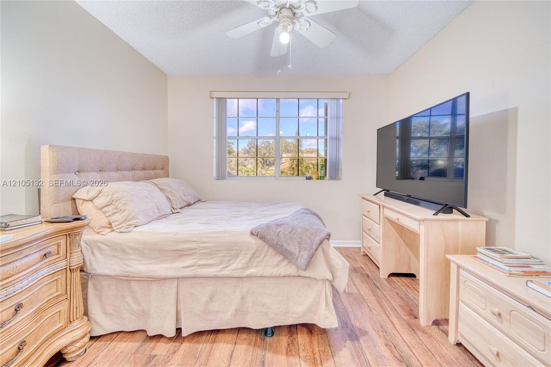 Recessed window with grid pattern, wood-finish flooring, vaulted ceiling, and ceiling fan