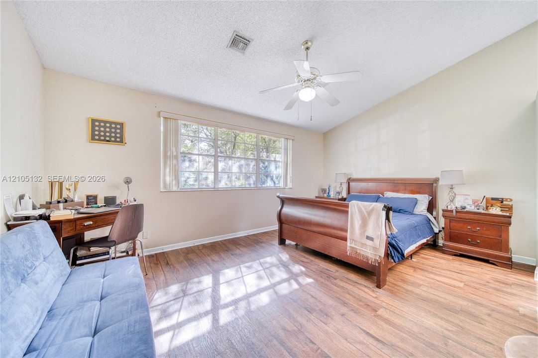 Wood-finish flooring, vaulted ceiling, ceiling fan with integrated lighting, large window with blinds, and neutral wall tones