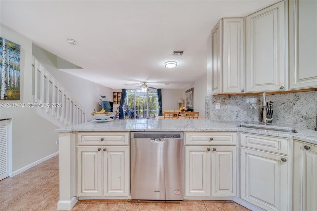 Kitchen featuring white cabinetry, light-toned countertops, a stainless steel dishwasher, and an undermount sink