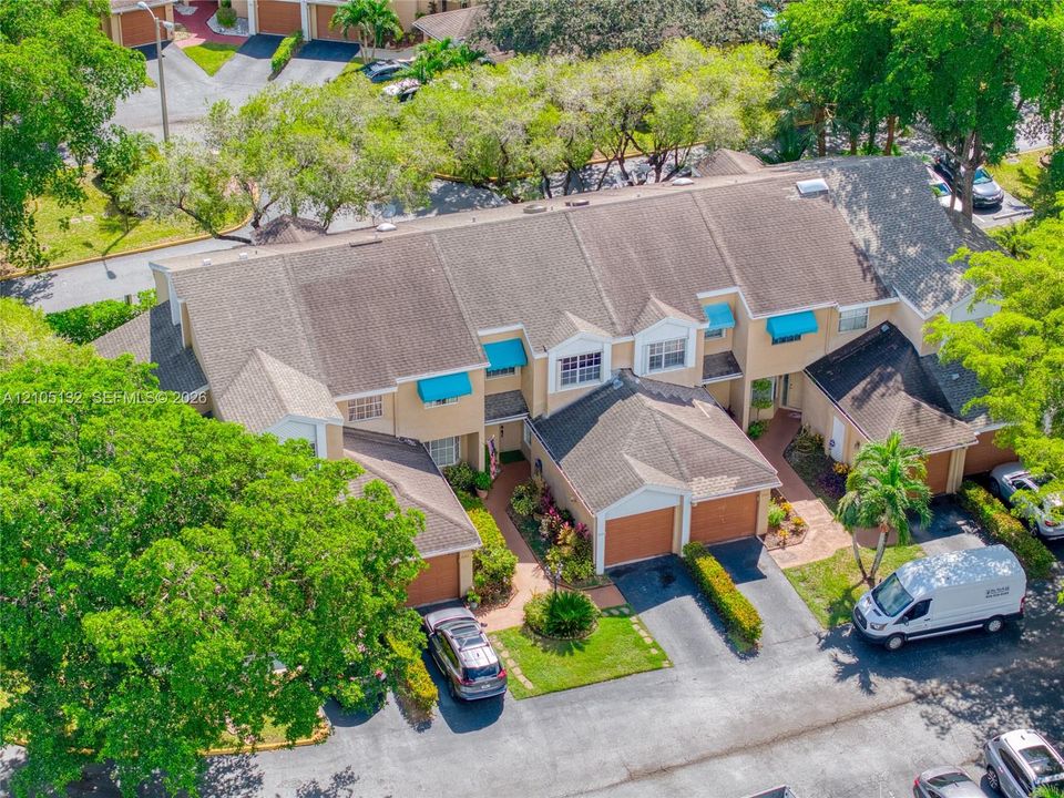Townhome community with terracotta roof tiles, individual garages, and mature landscaping