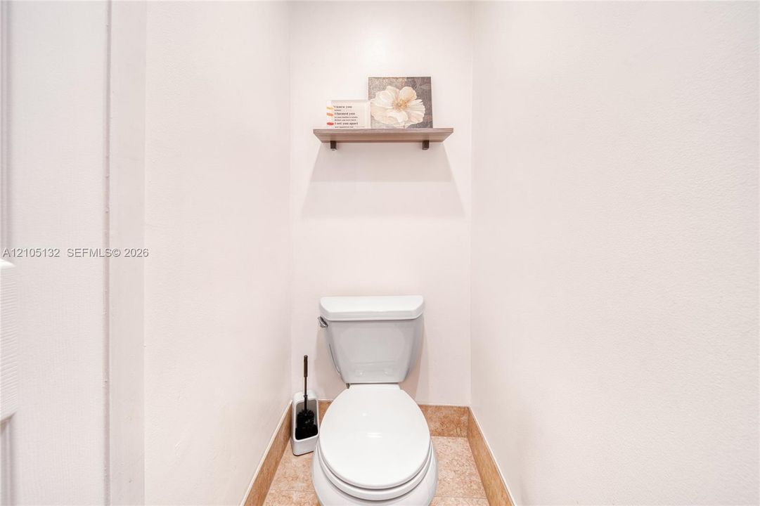 Built-in wall niche with wood-finish shelving above a commode
