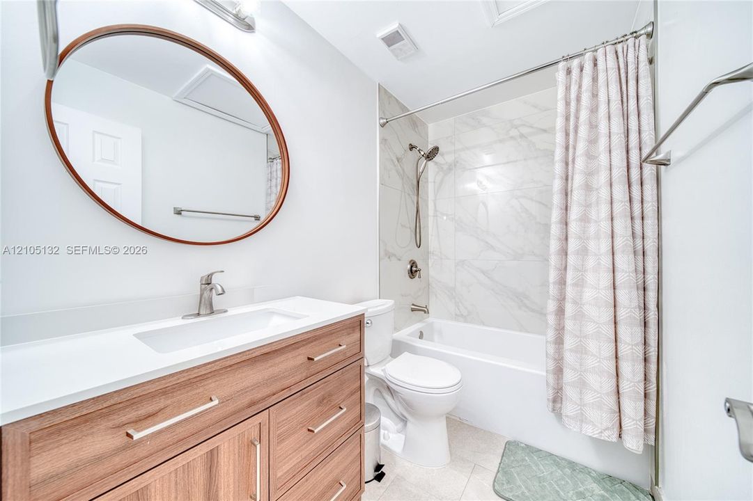 Wood-finish vanity with white countertop, undermount sink, and brushed nickel faucet