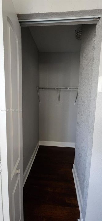 Closet with painted walls, dark wood-finish flooring, and a wire shelving system