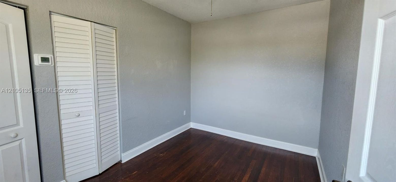 Wood-finish flooring, white louvered bifold closet doors, and a neutral wall color