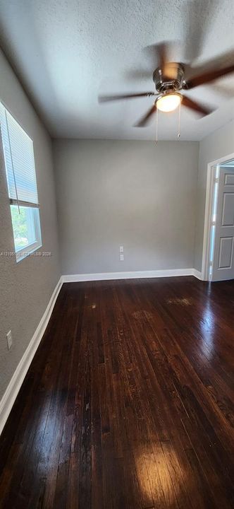 Rich wood-finish flooring, neutral wall tones, and a window with blinds