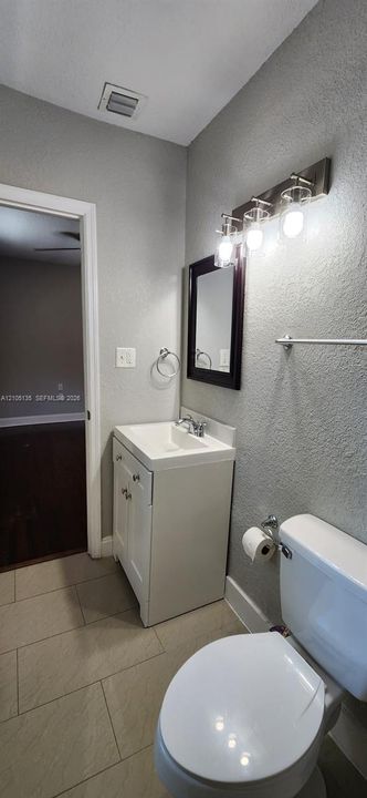 White vanity with a rectangular basin sink, chrome faucet, and rectangular framed mirror