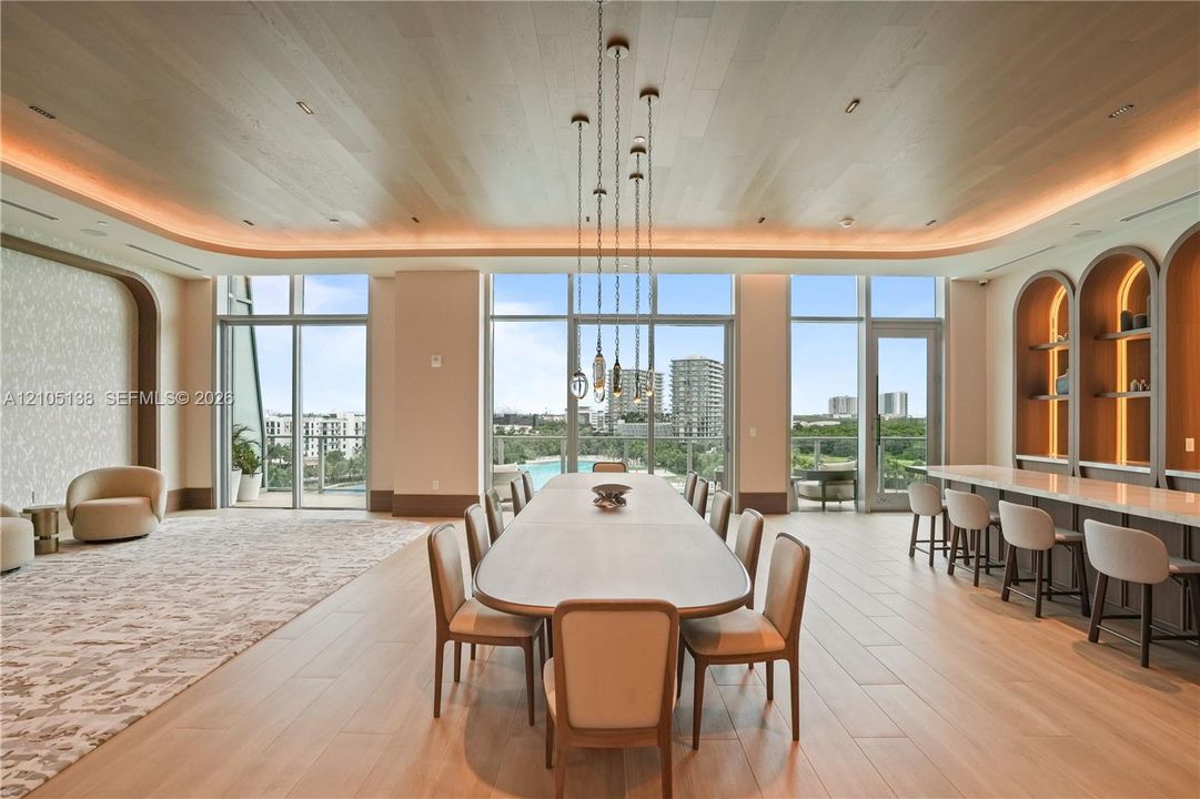 Expansive room featuring wood-finish flooring, a full wall of floor-to-ceiling windows, built-in shelving with arched accents, and recessed ceiling lighting