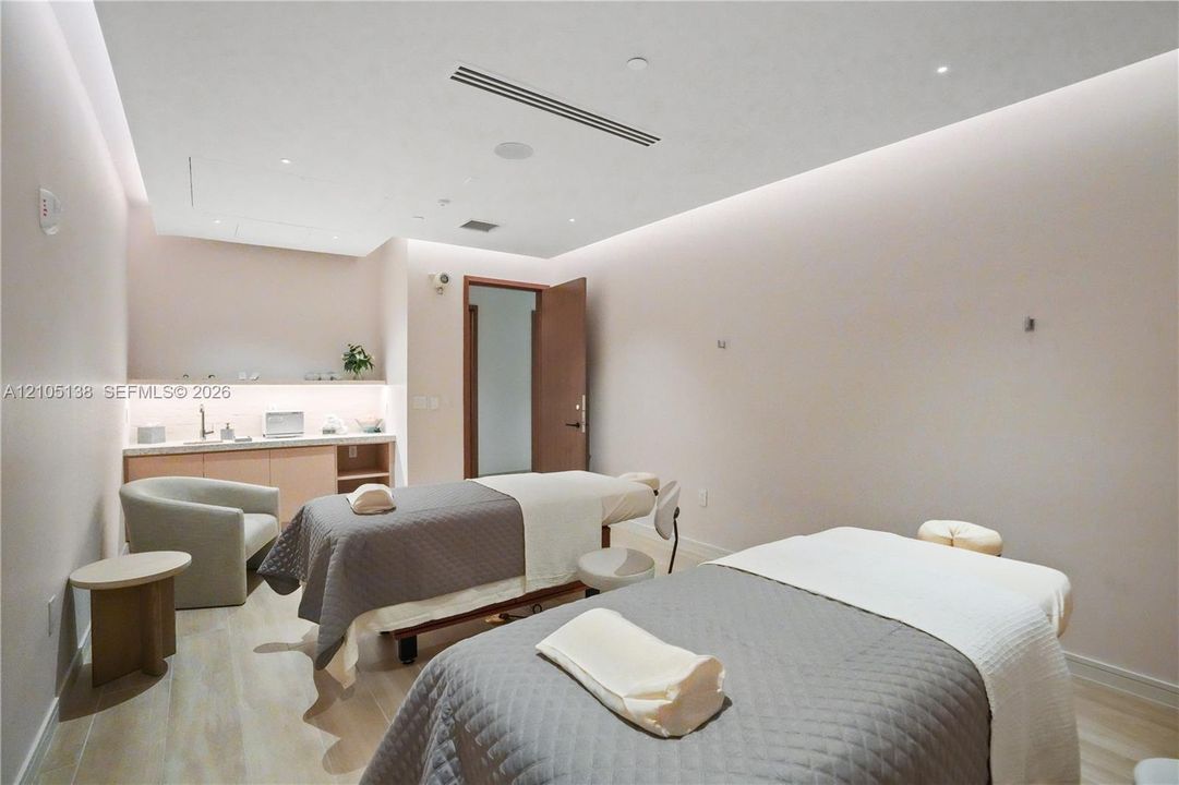Two treatment tables, recessed ceiling lighting, wood-finish flooring, built-in cabinetry with sink, and a solid core door