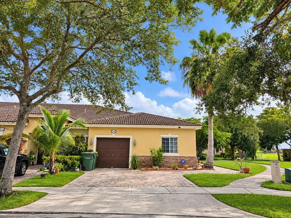 Stucco exterior with a tiled roof, paver driveway, and an integrated garage