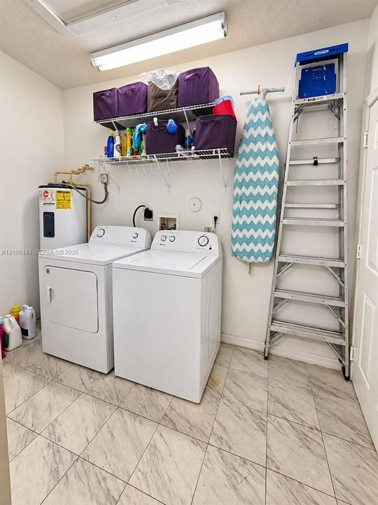 Tile flooring with a light-toned finish, wall-mounted shelving, and a water heater