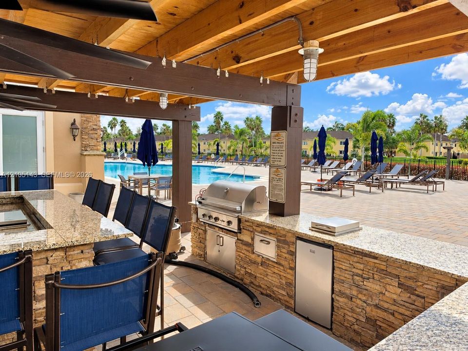 Outdoor kitchen with granite countertops, stone veneer base, built-in grill, and outdoor refrigerator