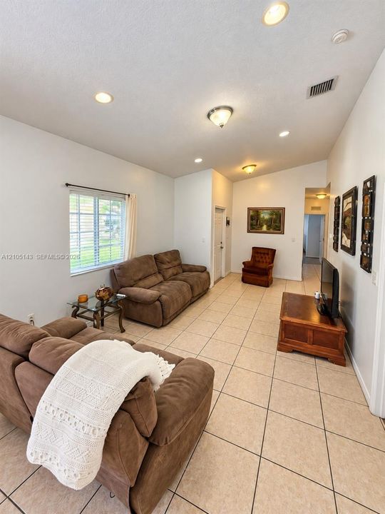 Recessed lighting, vaulted ceiling, tiled flooring, window with blinds, and white wall finishes