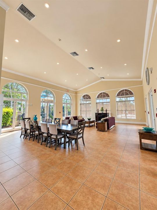 Spacious common area featuring large format tile flooring, vaulted ceilings, recessed lighting, and multiple arched windows