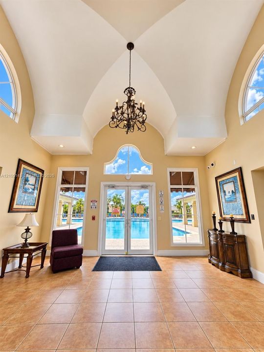 Vaulted ceilings featuring an ornate chandelier, arched windows, and tile flooring